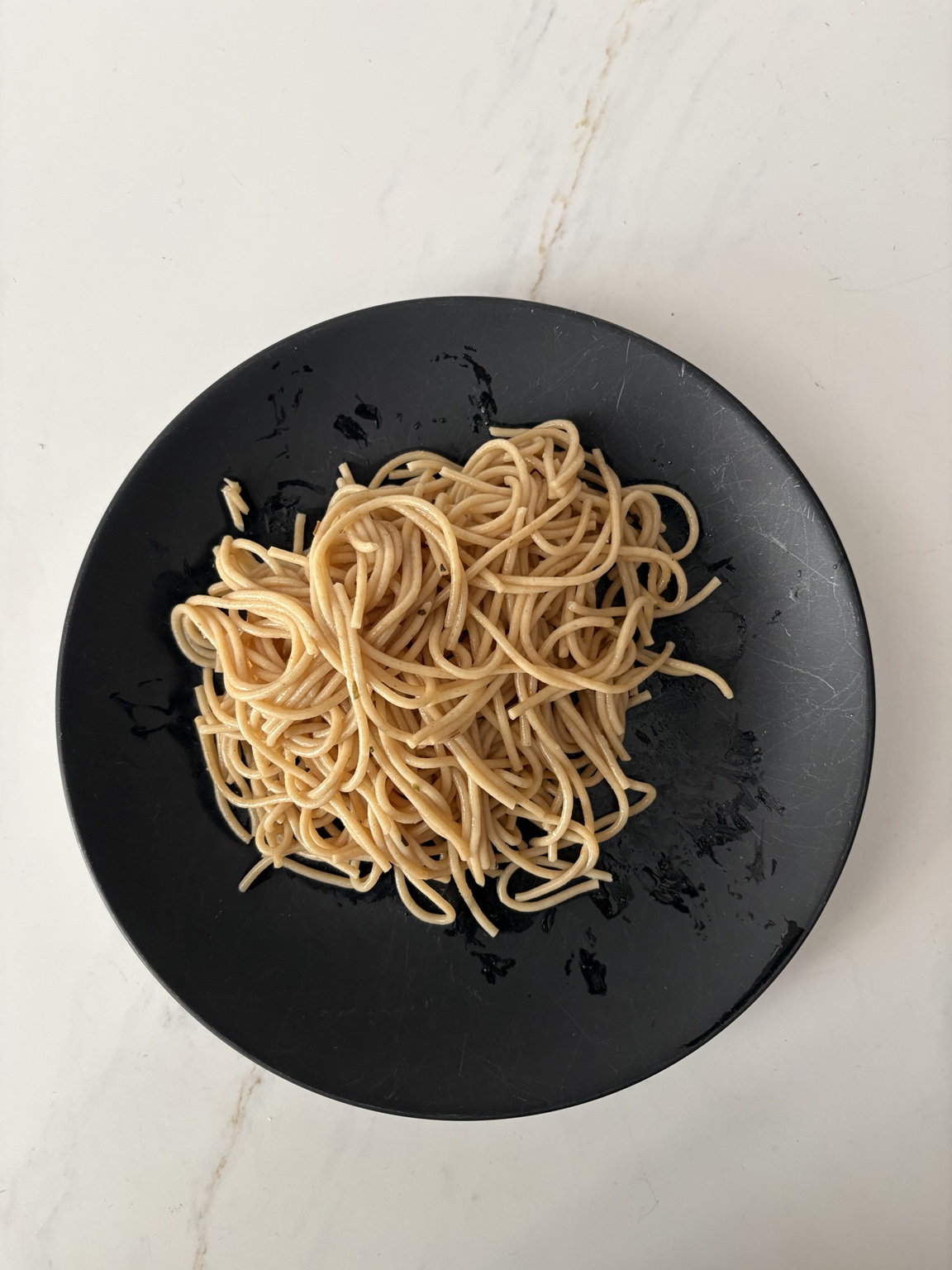 Overhead view of whole grain pasta on a black plate
