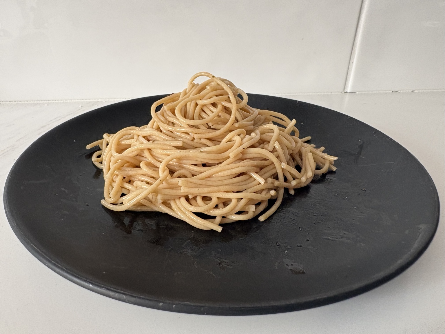 Side view of whole grain pasta on a black plate